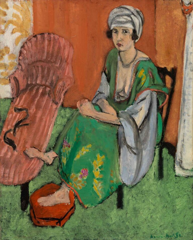 The Green Dress by Henri Matisse (1919): a seated woman wearing a green floral dress and gray wrap rests her hands in her lap, her bare foot in a red basin on a green carpet, beside a pink chaise longue and patterned orange and ivory wallpaper.