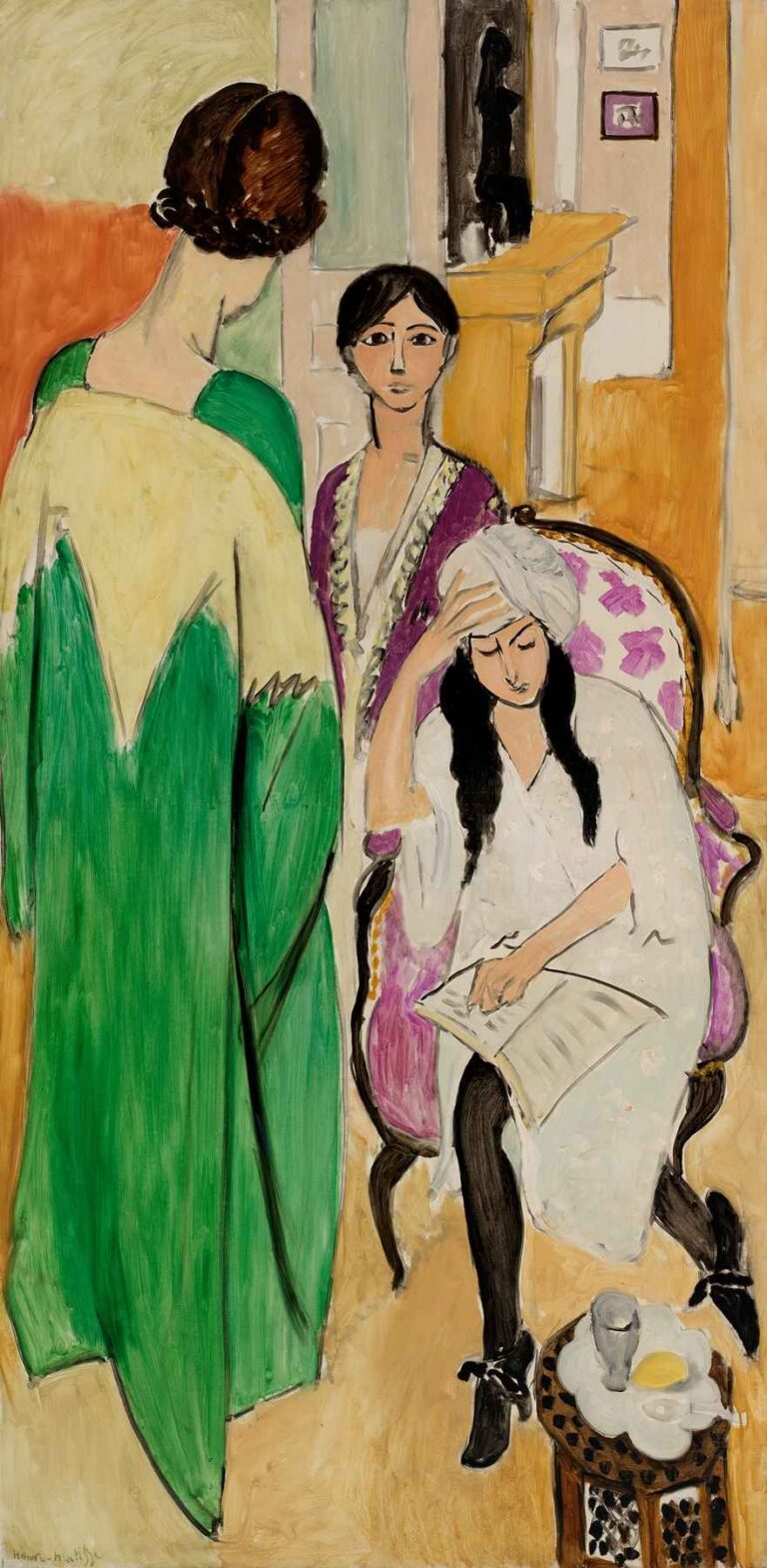 Three Sisters with an African Sculpture by Henri Matisse (1917): three women—one seated, two standing in green, purple, and ivory robes—pose in a richly patterned room with an ebony African statuette displayed above a mantel.