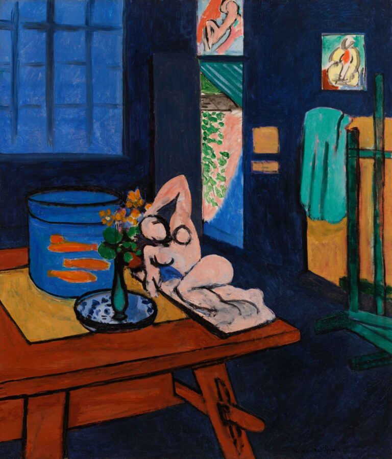 Studio with Goldfish by Henri Matisse (1912): a deep-blue interior with a red-brown table in the foreground holding two goldfish bowls and a green vase of yellow blooms, with an open door and window revealing greenery beyond and an easel draped in a green cloth.