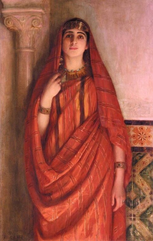 "Young Tunisian" by Albert Aublet, depicting a young North African woman standing in a graceful pose, wearing a flowing red striped burnous with gold jewelry. She stands against a background of cream-colored architecture with a fluted column on the left and colorful geometric tilework on the right. The soft lighting emphasizes the warm tones, detailed fabrics, and calm dignity of the subject.