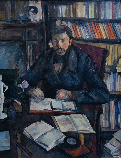 Painting "Gustave Geffroy" by Paul Cézanne. The seated figure of French art critic Gustave Geffroy sits at a desk covered with open books and papers, surrounded by shelves filled with colorful books. A small sculpture and a single flower sit on the desk. Cézanne's brushstrokes create a structured yet fragmented space, blending deep blues, browns, and muted tones in an unfinished composition that balances form and abstraction.