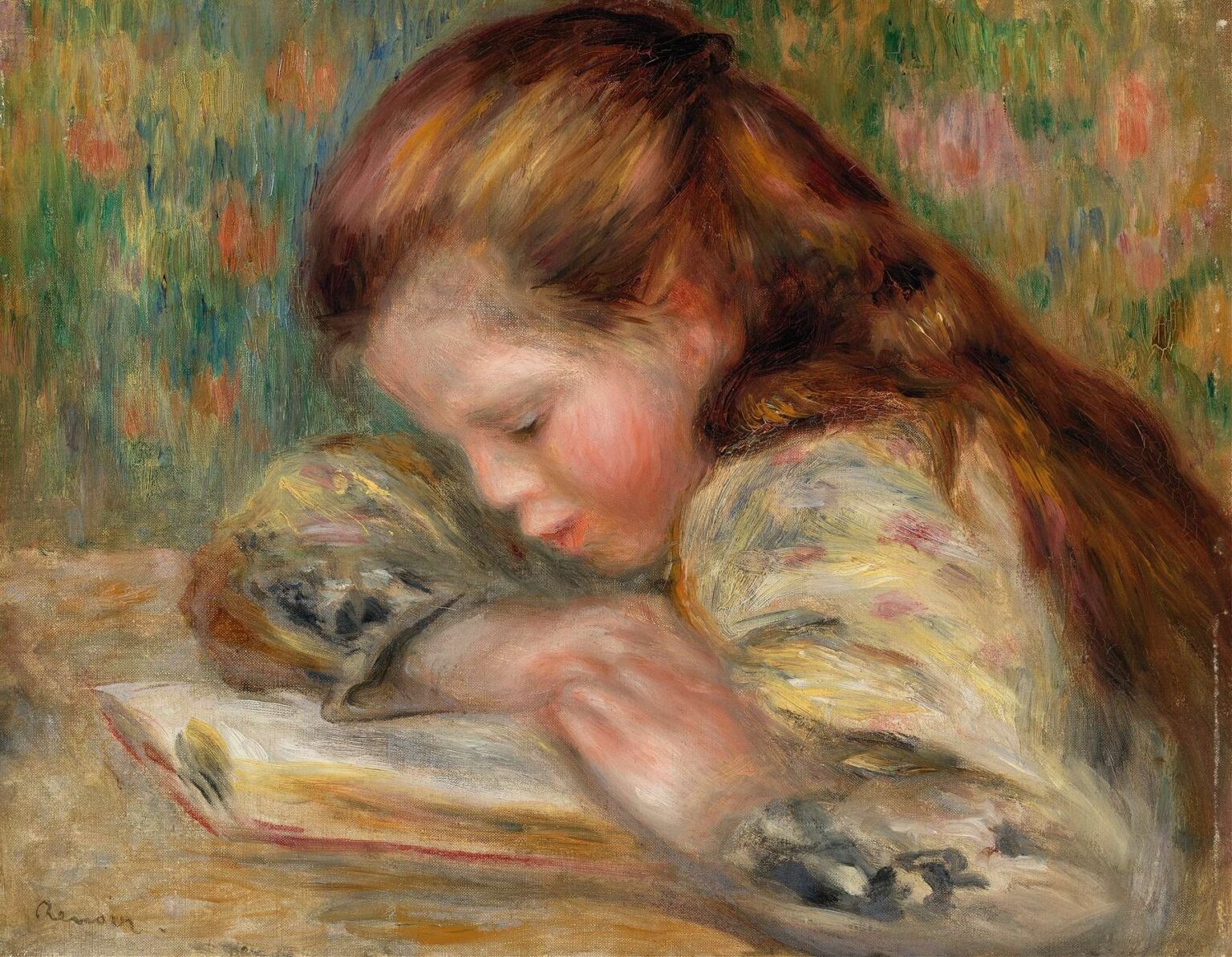 A young girl resting her head on folded arms atop a table reads an open book, her russet hair and rosy cheeks illuminated by soft light against a decorative green‑and‑coral wallpaper.