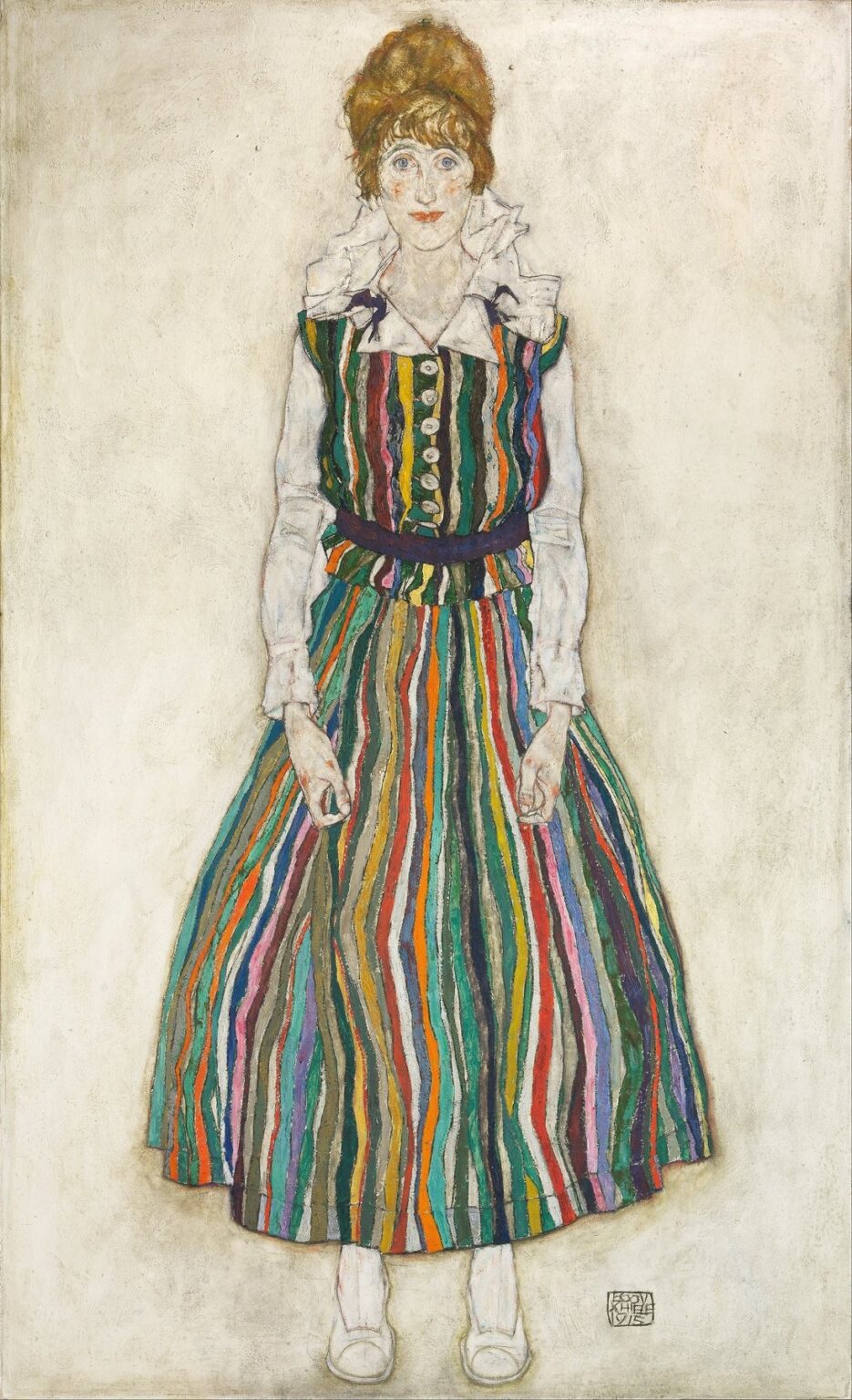 Full-length portrait of Edith Harms by Egon Schiele showing her standing against a pale background in a multicolored striped dress, white blouse, and white slippers, outlined in expressive black lines with an intense direct gaze.