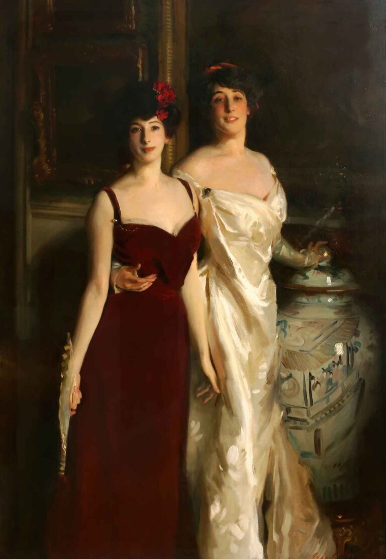 Two young girls in elegant evening gowns stand side by side against a dark interior; one wears a crimson dress holding a pale fan, while the other wears ivory beside a large porcelain vase.