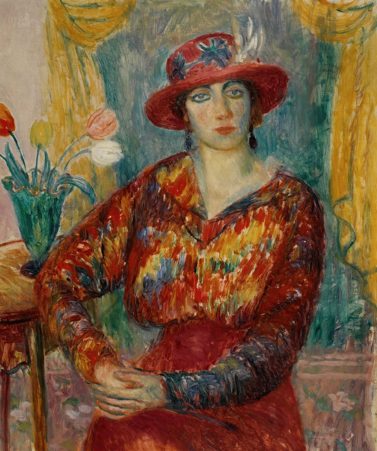 A seated woman in a red patterned blouse next to a vase of tulips, painted in impressionistic strokes with warm reds and cool greens.