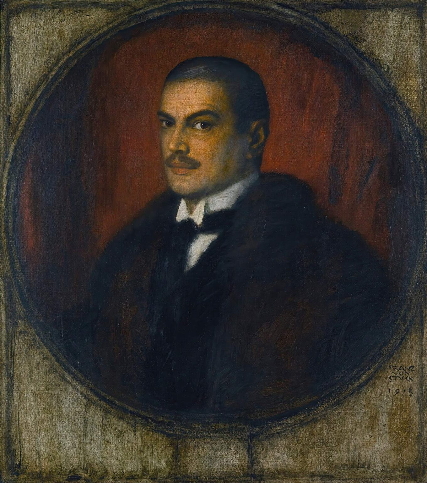 Oil painting of Franz von Stuck in three‑quarter profile, wearing a dark cloak and white collar, set in a painted stone rondel against a glowing red background, with a solemn, intense gaze.