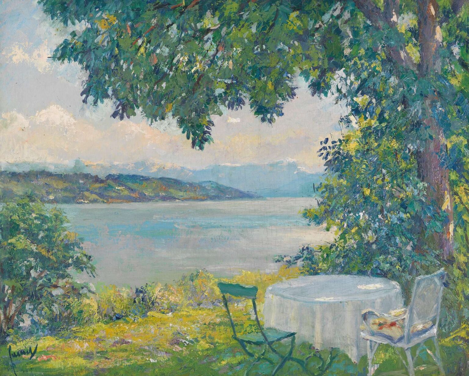 A lakeside scene with a white table draped in cloth and two chairs under leafy green trees, overlooking a calm blue lake with distant hills on the horizon.