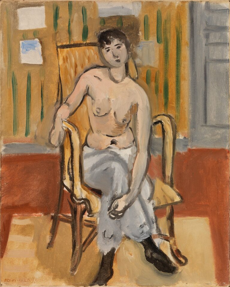 Oil painting of a nude woman seated in a cane-back chair within a tan, shallow room; she wears a gray-blue wrap around her legs and black footwear, rests one arm on the chair, tilts her head toward the viewer; ochre walls with green vertical accents, a gray door at right, and a terracotta floor painted with loose, expressive brushwork.