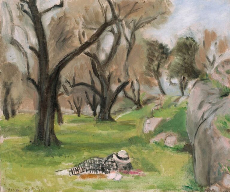 A sunlit grove with dark curving tree trunks, pale sky, and fresh green grass. A person in a checked outfit lies resting in the foreground near rounded rocks on the right. Thin, visible brushstrokes and restrained color create a serene Mediterranean scene painted by Henri Matisse in 1923.