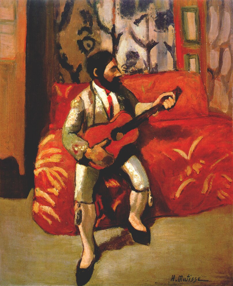 Interior scene of a bearded man in a pale suit playing a red guitar while seated on a bright red patterned sofa; patterned wall behind, green-edged panel at right, gray floor below; strong dark contours and simplified planes create a warm, shallow, decorative space.