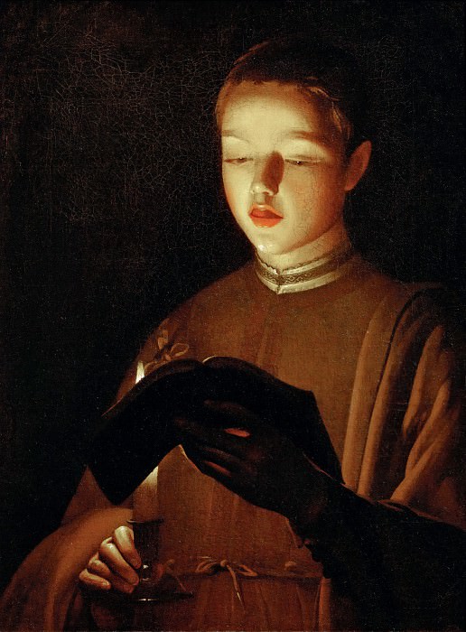 Candlelit portrait of a boy singing from an open book; he holds a candlestick in one hand while warm light illuminates his face, lips, and pages against a dark background.