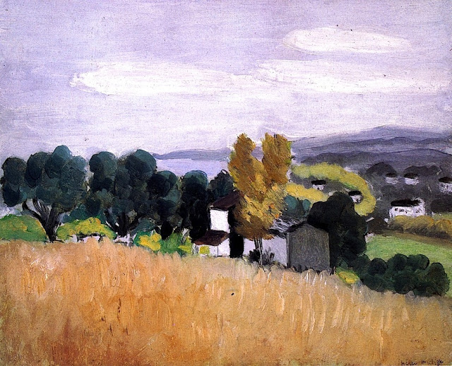 Landscape by Henri Matisse showing a broad golden wheat field in the foreground, a cluster of dark green trees with two ocher-yellow trees and simple white houses in the middle ground, and soft blue-gray hills under a pale lavender sky; simplified forms and tempered colors evoke autumn in the south of France.