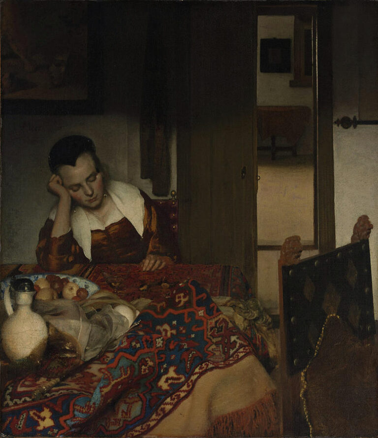 In a dim Delft interior, a young woman dozes at a table draped with a rich Turkish carpet beside a white wine jug and fruit, while a half-open door reveals a quiet back room in cooler light.