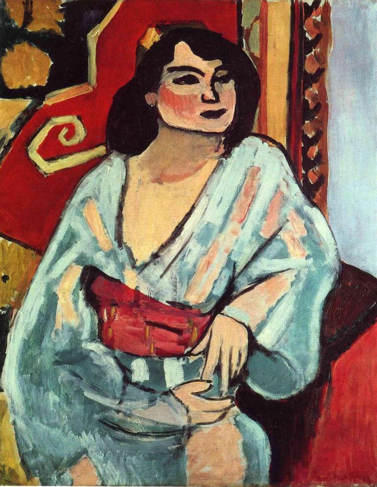 A seated woman in a pale blue-gray robe with a vivid red sash faces left before a red patterned backdrop; firm black contours, simplified features, and broad color planes create a decorative, modern portrait in Matisse’s 1909 “Algerian Woman.”