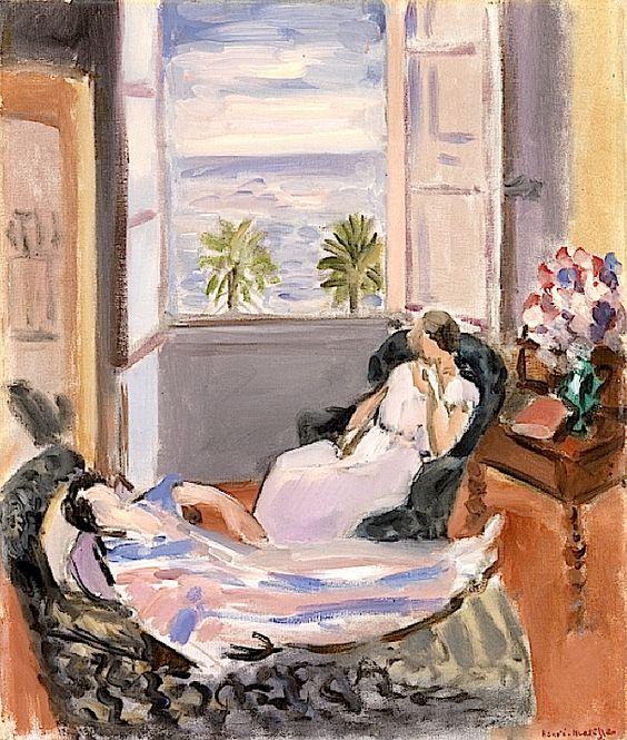 Sunlit room with a large open window showing blue sea and palms; one woman reclines on a patterned chaise while another sits in an armchair facing her; a small table with a bouquet and red book stands at right; soft pinks, violets, and terracotta tones create a calm Nice-period atmosphere.