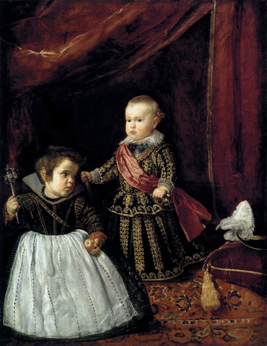 Two richly dressed children stand on a red carpet beneath heavy crimson drapery; the blond prince Don Baltasar Carlos faces forward with a sash and lace collar while a young court dwarf beside him holds a rattle and fruit near a cushioned stool with a plumed hat.