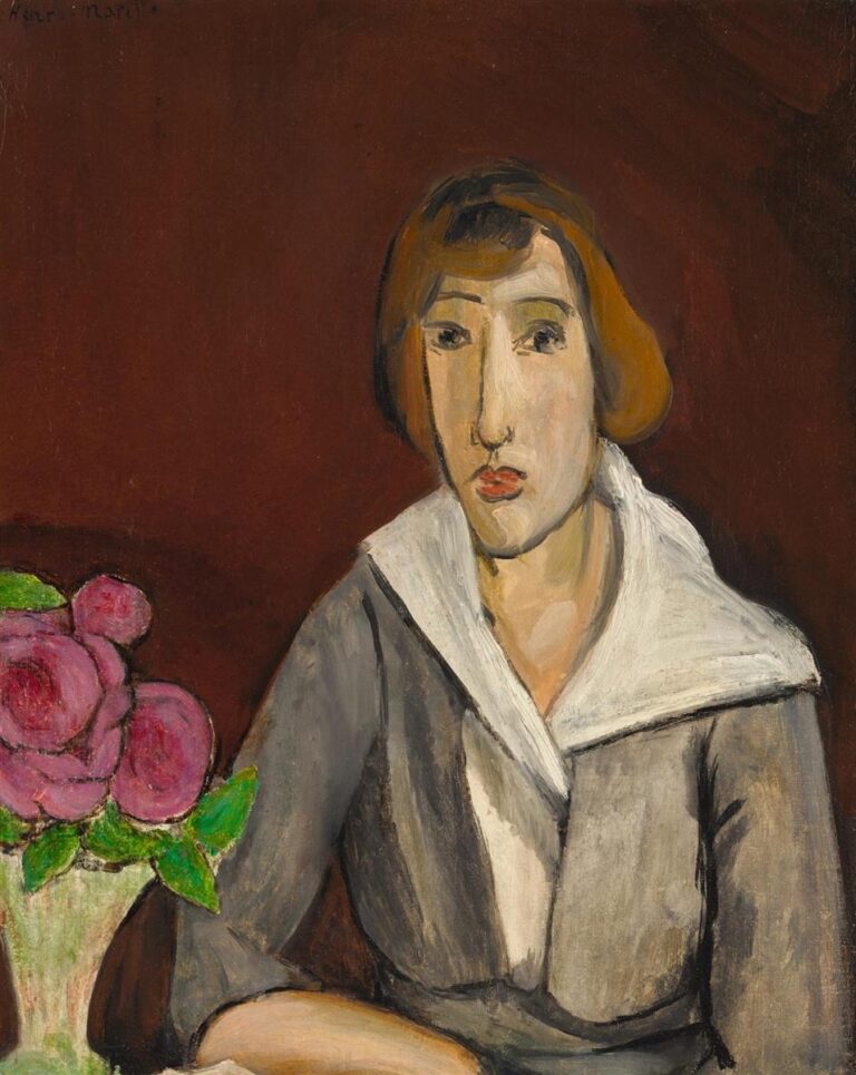 A seated woman in a gray dress with a crisp white collar poses before a deep red wall; a small vase of bright pink roses sits at her side. Simplified features, firm black contours, and visible brushwork create a calm, balanced interior typical of Matisse in 1918.