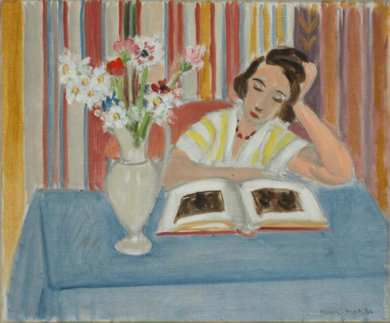 Calm interior with a woman reading at a table covered in blue cloth; a pale ceramic vase of mixed flowers stands to her left; behind her hangs a curtain of vertical multicolored stripes; soft light, gentle colors, and simplified forms characteristic of Matisse’s Nice period.