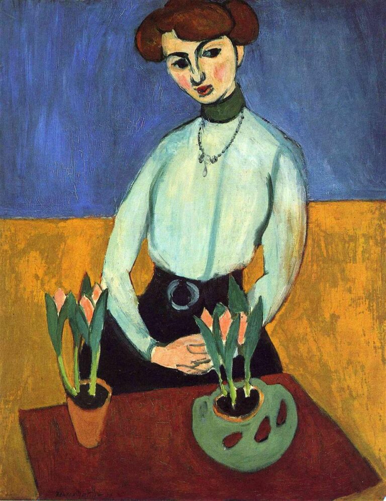 Young woman with head slightly tilted stands behind a diagonal table holding two pots of tulips; she wears a pale blouse with a dark skirt and green choker, hands clasped at a belt with a silver ring; background divided into a mauve-blue upper wall and ochre lower band in Henri Matisse’s 1910 “Girl with Tulips.”