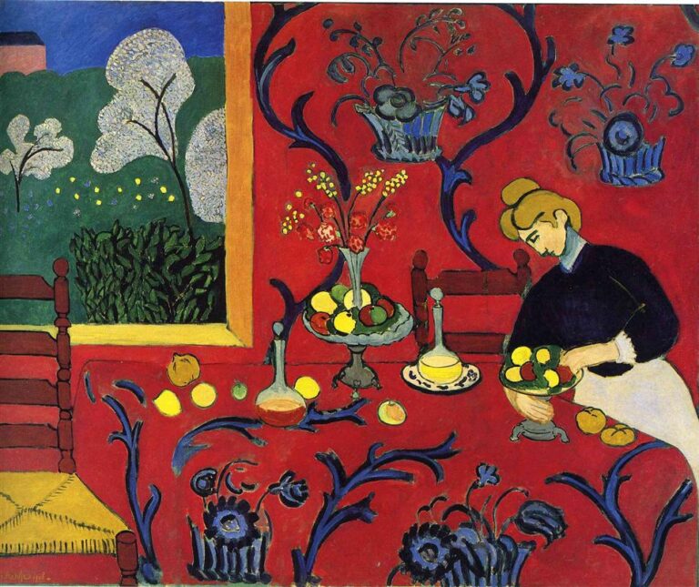 An intense red dining room merges table and wall under swirling blue floral patterns; a woman in a dark blouse arranges fruit among bowls, bottles, and flowers, while a yellow-framed window opens to a green garden with blossoming trees and a small house in the distance.