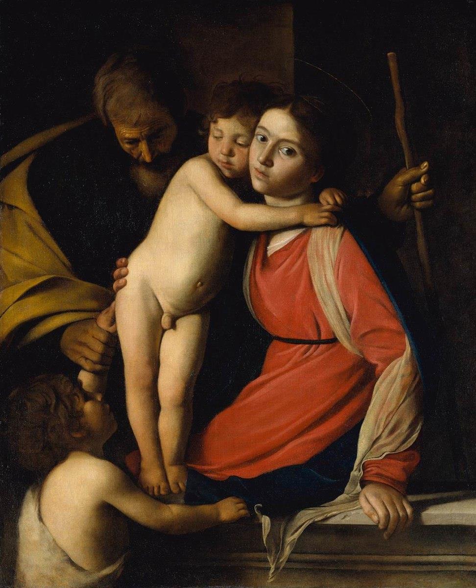 In a dark interior Mary holds a sleeping Christ Child while Joseph supports him from the left and young John the Baptist reaches up; a staff rises behind Mary, and strong light models faces, hands, and red-blue drapery against deep shadow.