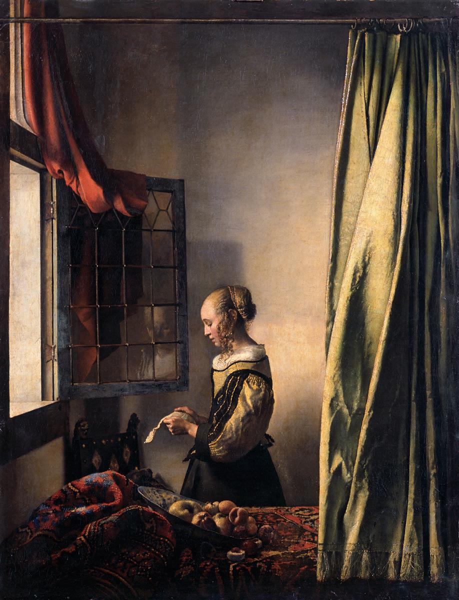 A young woman stands by an open casement window reading a letter; morning light illuminates her gilded bodice, a bowl of fruit on a carpeted table, a green curtain at right, and a large Cupid painting on the back wall.