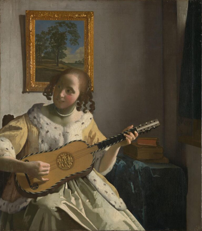 Half-length view of a young woman in satin and fur playing a small guitar; she looks to the left while sunlight highlights her pearls and curls, with a gold-framed landscape behind and a few books on a table to the right.