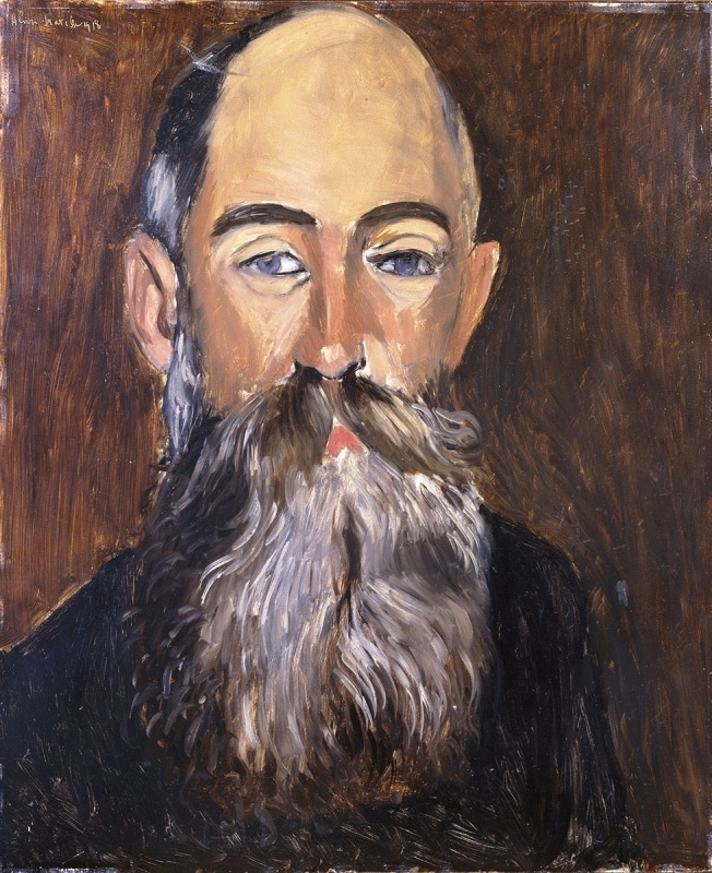 Frontal head-and-shoulders portrait of a bald, bearded man with cool blue eyes; large flowing gray beard painted in lively strokes; warm brown background; restrained palette and strong contours characteristic of Matisse’s 1918 Nice-period portraits.