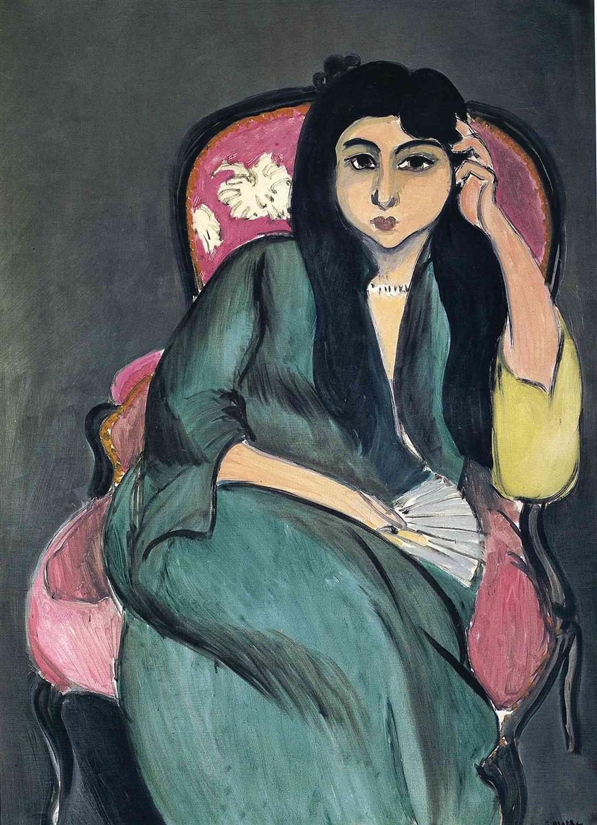 Seated portrait by Henri Matisse of Laurette in a flowing green robe on a pink upholstered chair against a flat gray background; black hair frames her face, one hand supports her temple, a pale fan rests near her lap, and a small yellow sleeve accent brightens the right side; strong black outlines and broad color fields convey calm and modernity.