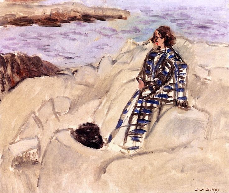 Woman in a blue-and-black patterned coat seated on pale rocks above a violet sea; dark cap or rock in the foreground, distant brown ledges across the water; quick brushstrokes and soft coastal light characteristic of Matisse’s Nice-period style.