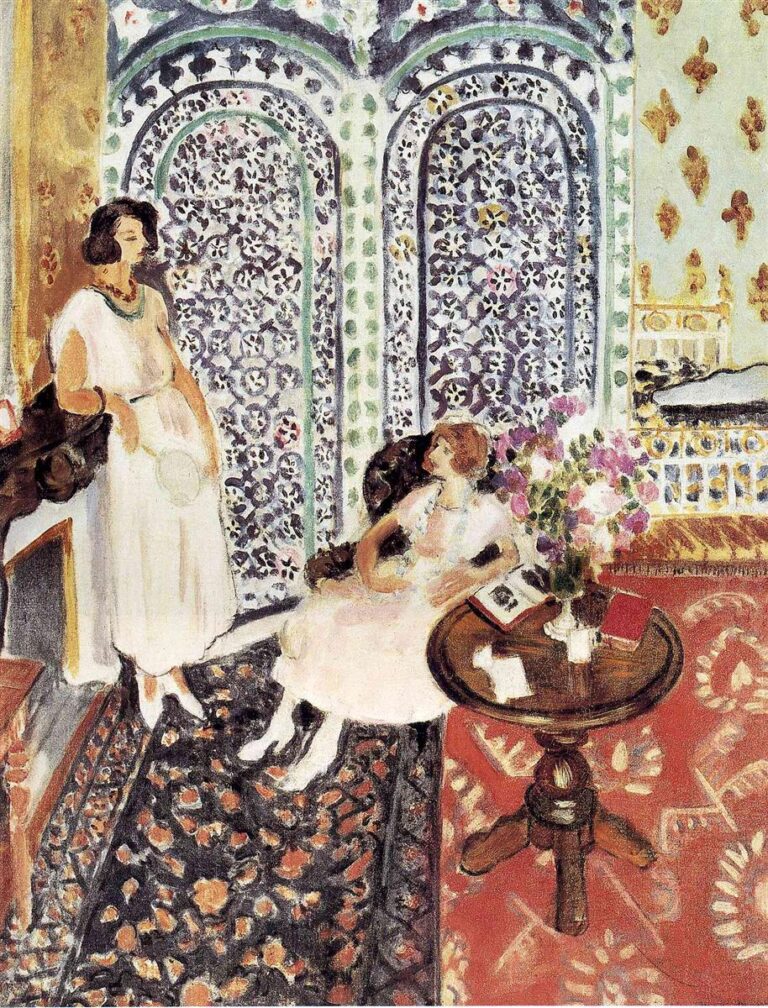 Interior with two women in white dresses beside a round table of flowers; dark floral carpet meets a red patterned rug; behind them a twin-arched Moorish screen of blue, mint, and charcoal arabesques rises like a lace wall, painted in Matisse’s airy Nice-period style.