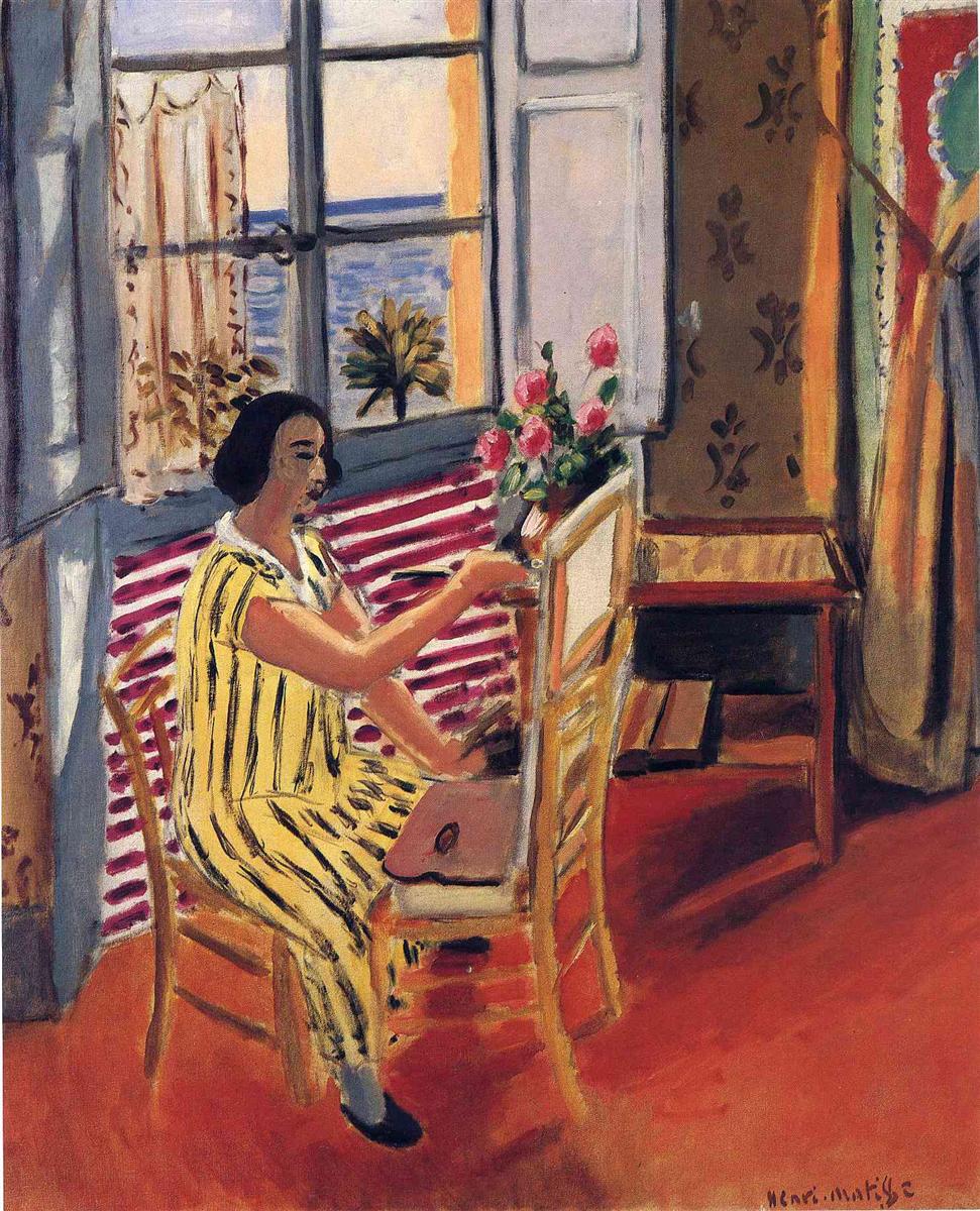 Interior by Henri Matisse showing a woman in a yellow striped dress seated at an easel in a sunlit room, with pink flowers on a table, patterned walls and curtain, and an open window revealing the Mediterranean sea.