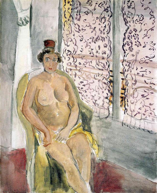 A nude woman wearing a small red cap sits in a yellow armchair beside tall windows with mauve lace curtains; gray floor and a red carpet anchor the interior, painted by Henri Matisse in 1920.