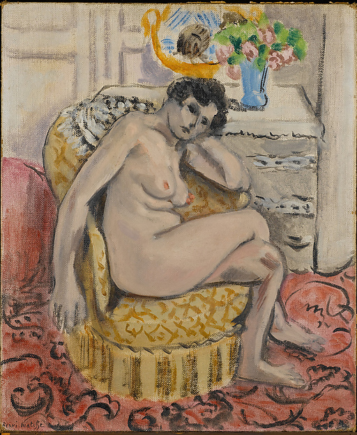 A seated nude woman reclining in a plush yellow armchair within a pale interior, surrounded by a pink patterned carpet, a side table with a blue vase of flowers, and a yellow fruit dish, painted by Henri Matisse in 1920.