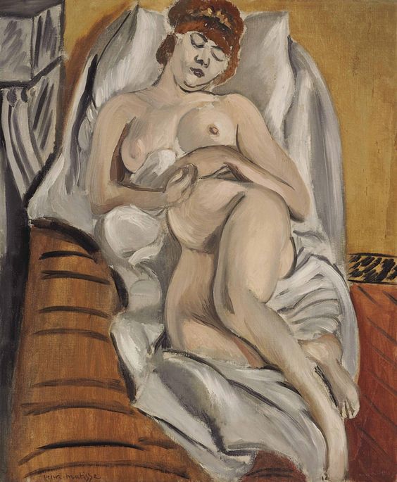 Reclining nude woman with eyes closed on white pillows and sheets, one hand on chest and one on abdomen, warm ochre bolster at left and brown floor at right; simplified planes, soft gray shadows, and clear contours characteristic of Matisse’s 1915 style.