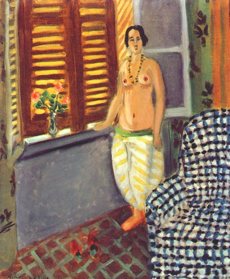Interior by Henri Matisse showing a standing bare-chested woman in white trousers with yellow stripes beside a shuttered window and vase of flowers, with red slippers on a tiled floor and a blue-black checked armchair in the foreground, painted in 1925.