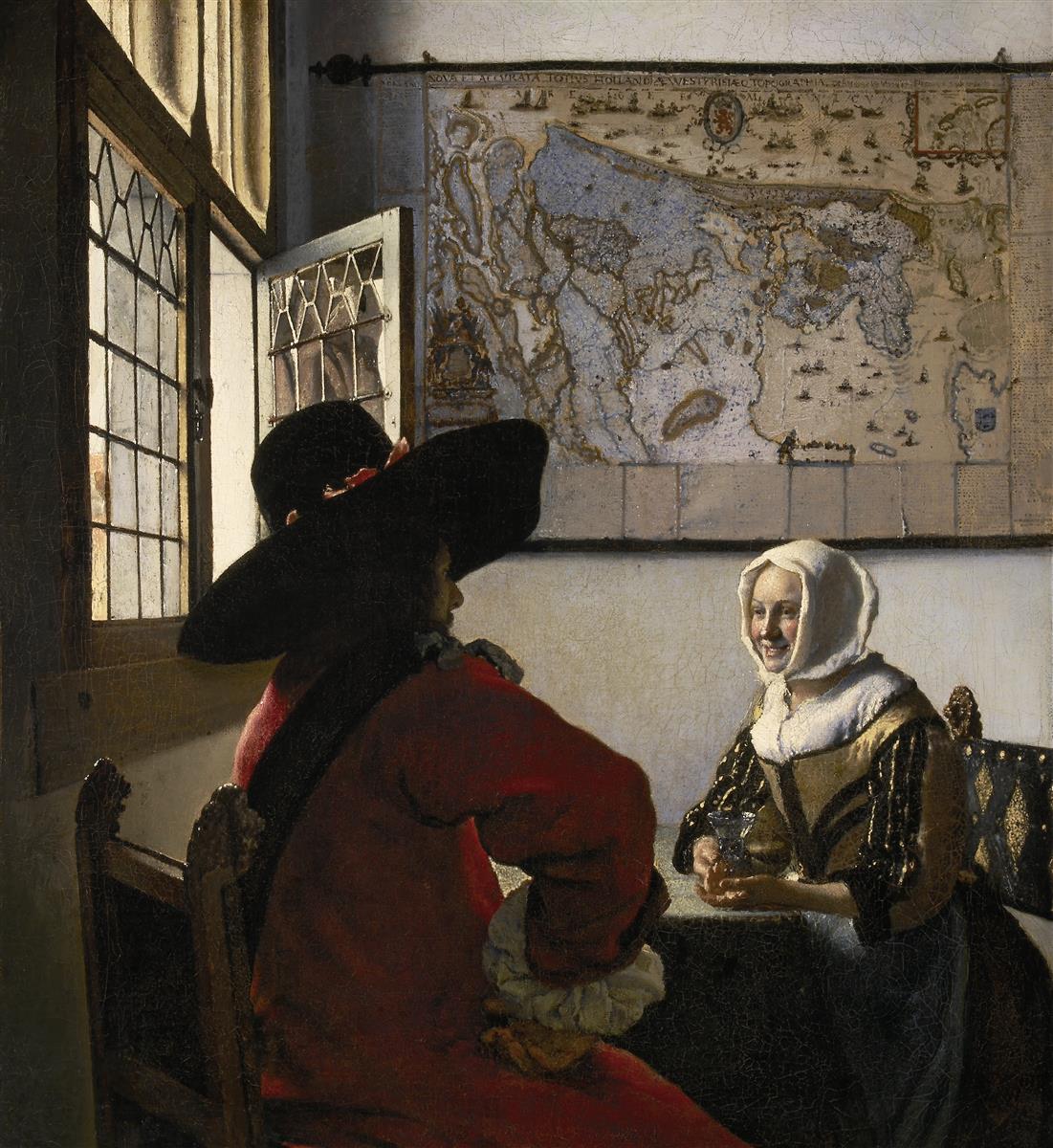 A soldier in a large black hat and red coat sits with his back to the viewer facing a smiling woman who holds a wineglass, while bright daylight enters through leaded windows and a large wall map hangs behind them.