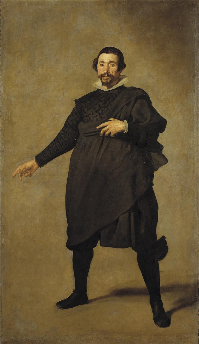 Full-length portrait of the actor Pablo de Valladolid standing in a neutral-toned void, one hand extended in a speaking gesture, dressed in black with a white collar and casting a soft shadow on the ground.