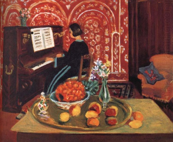 An interior shows a woman in profile playing an upright piano before a red, floral patterned wall; in the foreground a brass tray holds peaches and apricots beside a basket of oranges, a small faience bottle, and a vase of flowers, with a sofa at right in soft ochre tones.