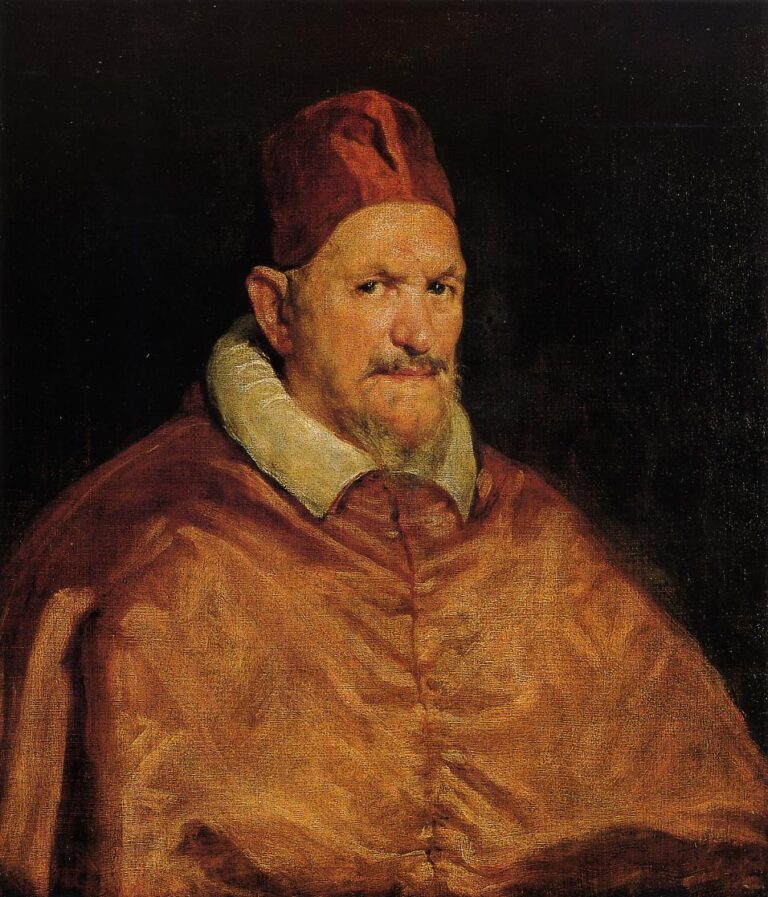 Half-length portrait of Pope Innocent X in scarlet robes and cap, pale fur collar and white shirtfront visible, seated against a dark background, his head turned three-quarters and eyes fixed with a wary, penetrating gaze.