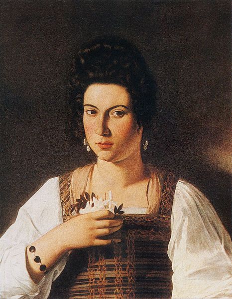 Half-length portrait of a dark-haired woman in a patterned bodice and white chemise, facing the viewer and holding a small cluster of flowers to her chest, with subtle jewelry and a dark plain background illuminated by soft directional light.