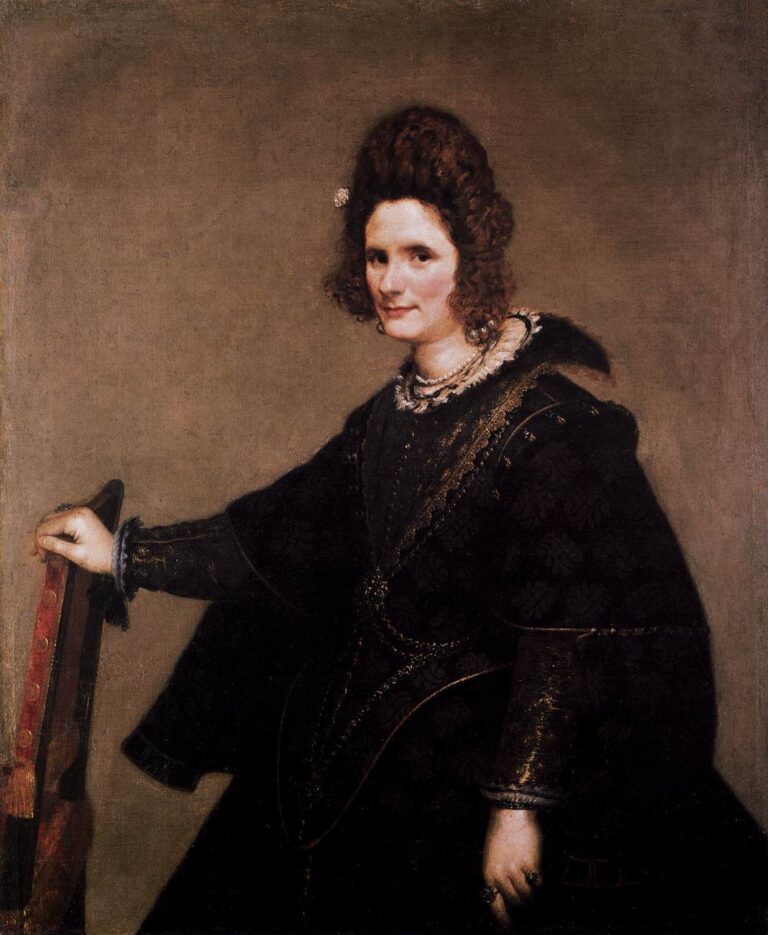 Three-quarter portrait of a woman in a dark Spanish dress with lace ruff and pearls, resting one hand on a red-trimmed chair and gazing toward the viewer against a soft, neutral background.