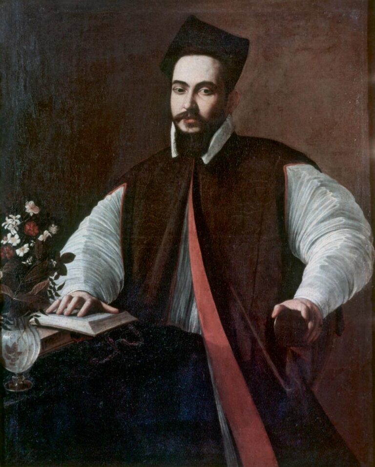 A seated young cleric wearing a black mozzetta, red sash, and biretta rests one hand on an open book beside a glass vase of flowers and turns a calm, direct gaze toward the viewer, his white sleeves catching the light against a plain, dark background.