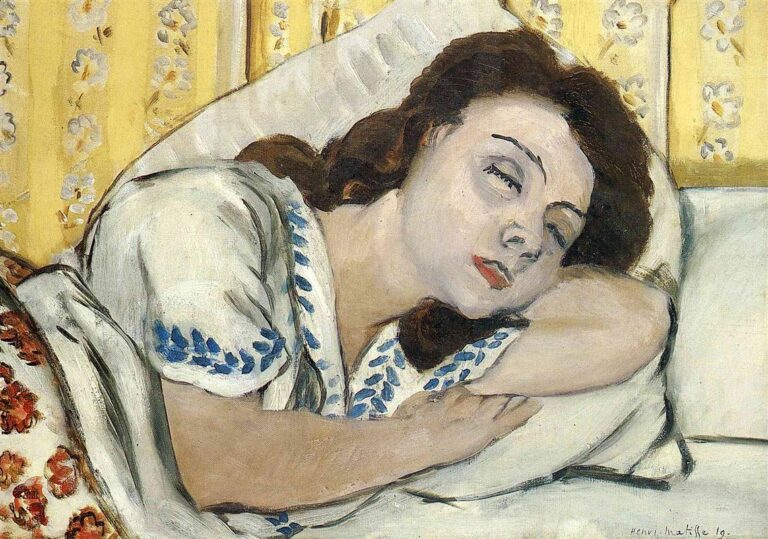 A close view of a young woman sleeping on her side with head on a white pillow, wearing a white blouse with blue embroidery before a yellow floral wall; her arm supports her face and her lips are softly red, painted by Henri Matisse in 1920.