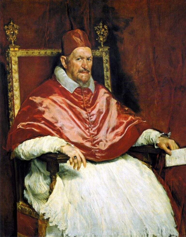 Full-length seated portrait of Pope Innocent X in scarlet cap and silk mozzetta with white rochet, holding a folded letter on a gilded chair before a red curtain, his wary eyes turned toward the viewer.