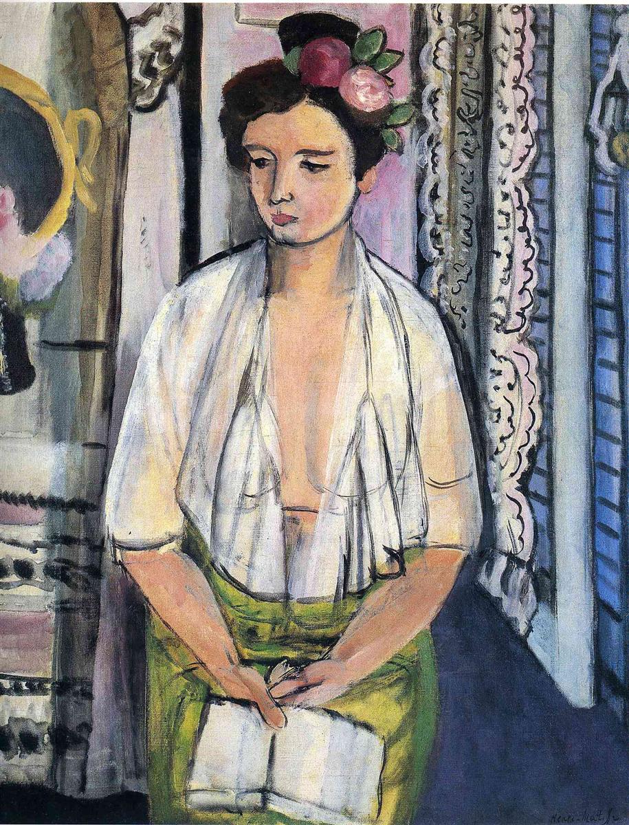 Half-length portrait of a young woman with a flower crown, open white blouse, and green skirt holding a pale book; flanked by a dark mirror and drapery on the left and lace curtains with blue shutters on the right; simplified forms, visible brushwork, and balanced black accents characteristic of Matisse in 1918.