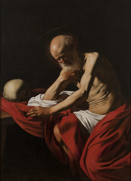 In a dark room, an elderly Saint Jerome sits wrapped in a red mantle, head bowed and hand to his chest, while a skull rests on a table beside him; a strong side light reveals ribs, shoulder, and folds of cloth against deep shadow.