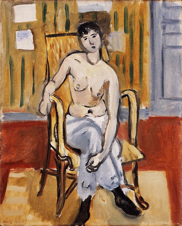 Half-draped woman seated in a yellow bentwood chair inside a tan room with vertical green strokes, red floor, and a blue door or shutter at right; white wrap over crossed legs, black shoe, simplified forms, and expressive black accents characteristic of Matisse in 1918.