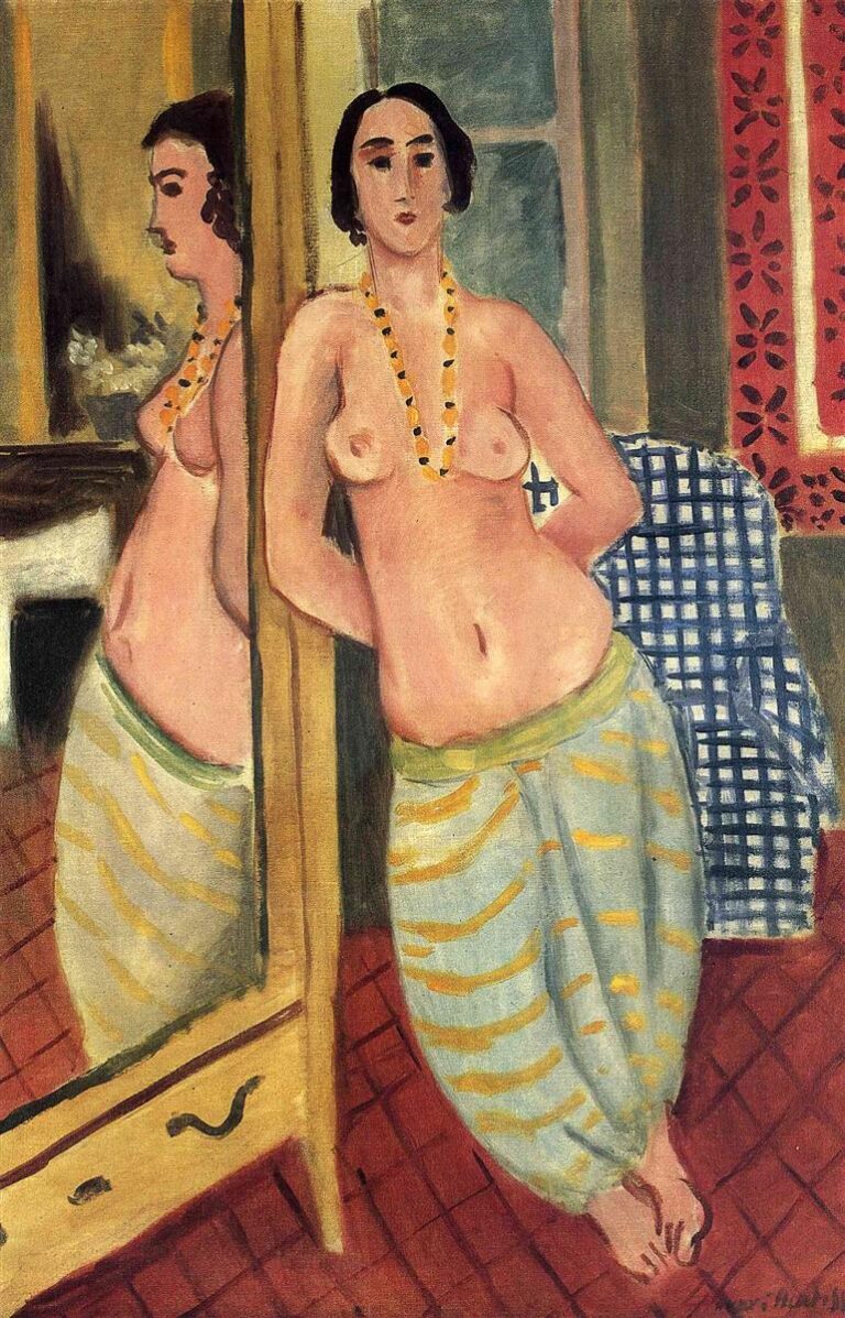 A topless woman in pale blue striped harem trousers stands beside a tall mirror that reflects her figure; she wears a yellow-and-black bead necklace, stands on a red tiled floor, with a blue-checked cloth and a red patterned curtain in a shallow, warmly lit interior.