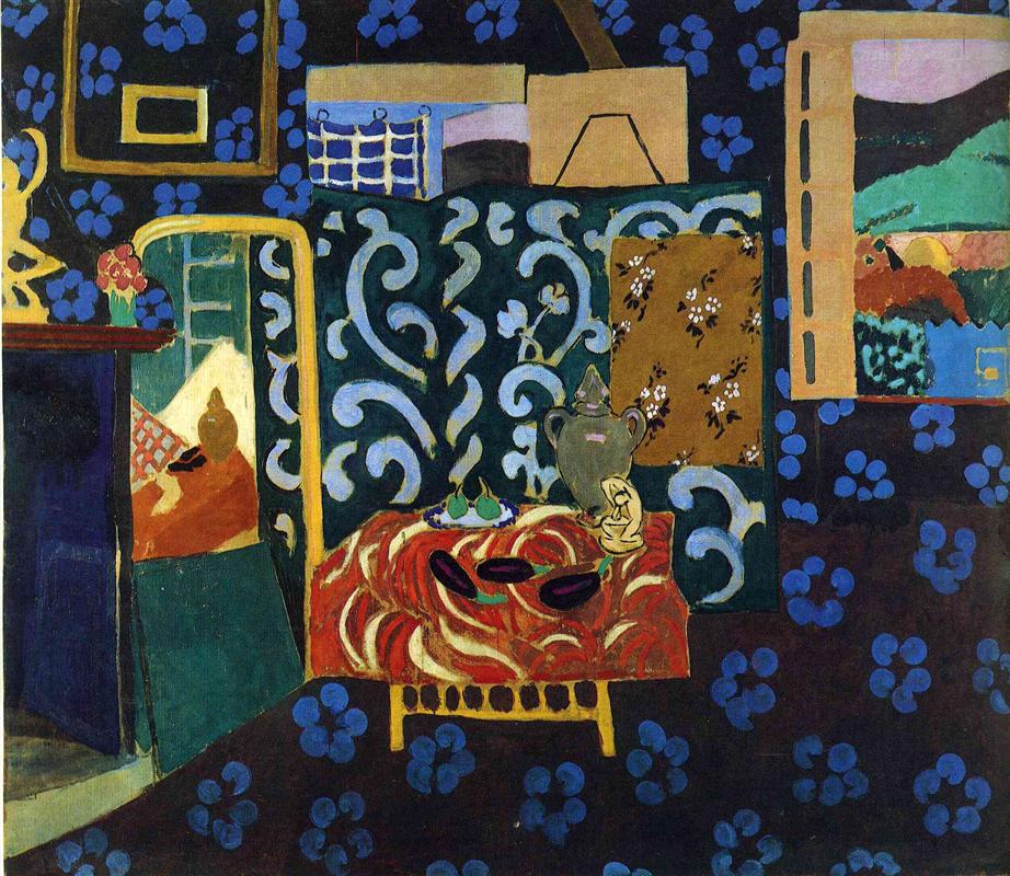 Dark blue interior patterned with bright blue florets; center foreground shows a low table draped in a red swirling cloth holding three dark aubergines, a lemon, and a pale green ewer; behind the table a tall teal screen painted with pale arabesques; to the right a golden-brown fabric patch and a small landscape; scattered frames and a small bouquet complete Henri Matisse’s 1911 “Still Life with Aubergines.”